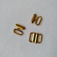 three gold metal clips sitting on top of a white surface