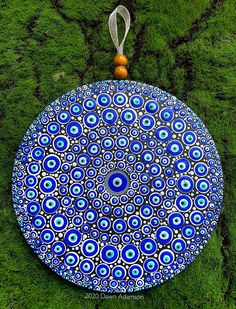 a blue and white plate sitting on top of green grass with an orange bead hanging from it