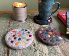 the table has two coasters and a candle on it next to a book with a cup