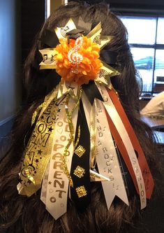 the back of a woman's head with ribbons attached to her hair and decorations on it