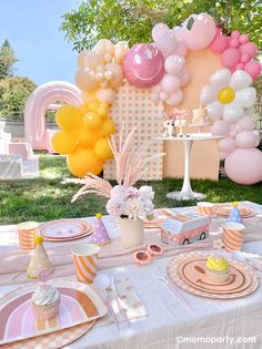 a table set up for a birthday party with balloons, cake and cupcakes