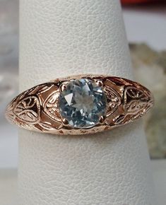 Natural Blue Topaz Ring Description Etched Wedding Design#160 Custom Here we have a Victorian/Edwardian reproduction ring in 14k rose gold with a stunning natural blue topaz gemstone. This full cut round cut genuine blue topaz is 6mm in diameter. The inside of the band is marked 14k for gold. Notice the beautiful floral design of the gold filigree setting. This is a lovely rendition of an Antique filigree wedding ring, and it is made ready to wear. A gift ring box is included and all rings are s Diamond Cut Blue Topaz Ring For Wedding, Victorian Blue Topaz Ring For Anniversary, Heirloom Blue Topaz Ring With Diamond Cut, Heirloom Blue Topaz Diamond Cut Ring, Victorian Topaz Ring With Accent Stones For Anniversary, Antique Topaz Ring For Anniversary, Antique Blue Topaz Ring For Wedding, Antique Blue Topaz Wedding Ring, Classic Blue Topaz Birthstone Ring For Weddings