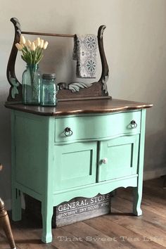 a green dresser with flowers and vases on top