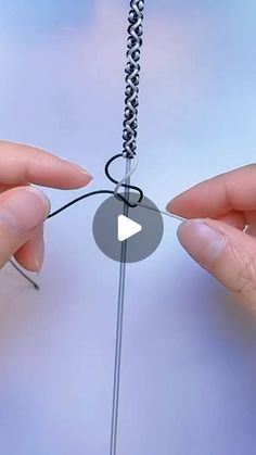 two hands are holding an object that looks like a wire with a knot on it