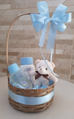 a teddy bear sitting in a basket with baby items inside it and a blue bow on the top