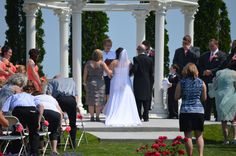 a bride and groom are walking down the aisle at their wedding ceremony in front of an outdoor gazebo