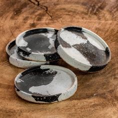 three black and white plates sitting on top of a wooden table next to each other