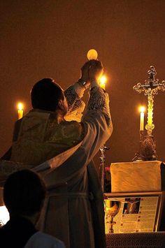 two people standing next to each other in front of a crucifix with candles