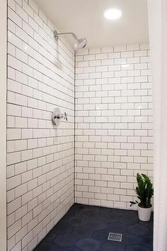 a white tiled bathroom with blue flooring and shower head mounted to the side of the wall