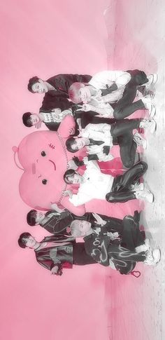 a group of people standing next to each other in front of a large pink teddy bear