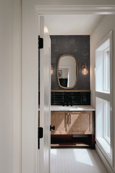 an open door leading to a bathroom with a sink and mirror on the wall above it