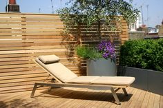 a lounge chair sitting on top of a wooden deck next to a potted plant