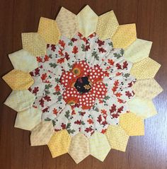 a close up of a flower on a wooden surface with many different colors and shapes