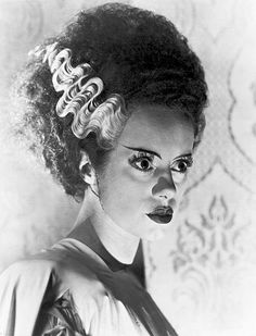 a black and white photo of a woman with curly hair in an old fashion hairstyle