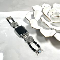 Chic beaded Apple iWatch band. Features Black and silver toned beads with crystal accents and a magnetic clasp for easy wear. Sizing Options: When measuring your wrist please provide your fitted wrist measurement (exact measurement of your wrist- this is very important!). I will adjust the size to allow for a little room for movement. If you have questions on how to measure, please contact me 😊Please note – due to sizing your bracelet may vary slightly from what is pictured. I may need to add o Elegant Silver Adjustable Apple Watch Band, Elegant Silver Watch Accessories With Bling, Luxury Silver Beaded Bracelet, Silver Bling Watch Bands As Gift, Adjustable Silver Beaded Bracelets With Bling, Silver Beaded Bracelets With Bling, Silver Bling Beaded Bracelets, Silver Beaded Stainless Steel Jewelry, Silver Apple Watch Band With Bracelet Strap