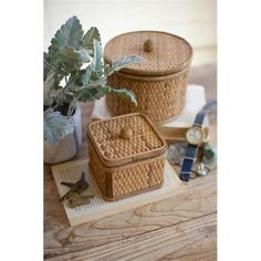 two wicker baskets sitting on top of a wooden table next to a plant and watch