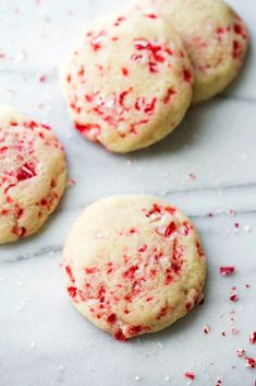 three white cookies with red sprinkles on top