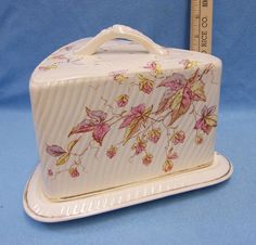 a white box with pink and yellow flowers on it next to a tape measure ruler