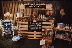 an outdoor bar made out of pallets and wooden crates with chalkboard signs on them