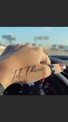 a person with a tattoo on their arm driving a car and writing it down the windshield