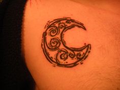 a crescent tattoo on the back of a woman's lower body, with swirls in it