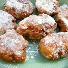 a green plate topped with powdered sugar covered donuts