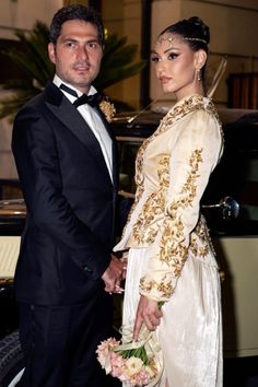 a man and woman standing next to each other in front of a car