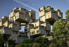 an unusual building with lots of windows and balconies on the top floor, in front of some trees