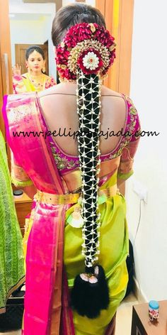 the back of a woman's saree with flowers in her hair and beads