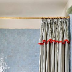 a bathroom with blue and white tile walls, shower curtain, and light fixture in the corner