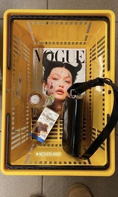 there is a magazine on the back of a yellow basket with a woman's face in it