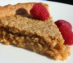 two raspberries sit on top of a piece of oatmeal pie