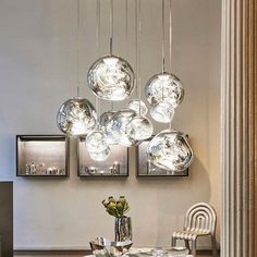 a dining room table with chairs and lights hanging from it's ceiling over it