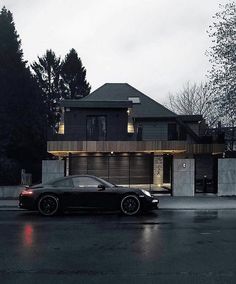 a black sports car parked in front of a house on a rainy day at night