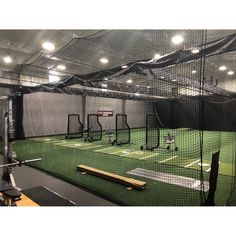 an indoor batting cage with lights on the ceiling and green grass in front of it