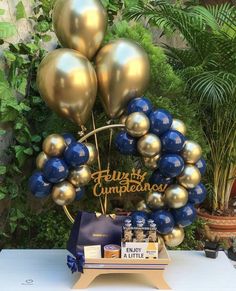 a bunch of blue and gold balloons are on display in front of a sign that says happy cumpetas