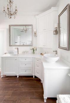 a white bathroom with two sinks and a chandelier