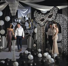 a man and two women are walking down the runway at a masquerade ball