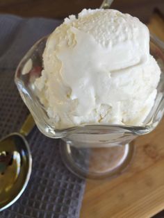 a scoop of ice cream sitting on top of a wooden table next to a spoon