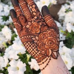 a hand with henna on it and white flowers in the background, all around