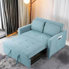 a blue couch sitting on top of a rug in front of a curtained window