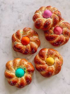 four buns with colorful candies and sprinkles sitting on a marble surface