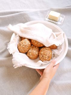 a person is holding a white bowl with some food in it on a tablecloth