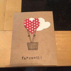 a brown card with red and white balloons in the shape of a heart on it