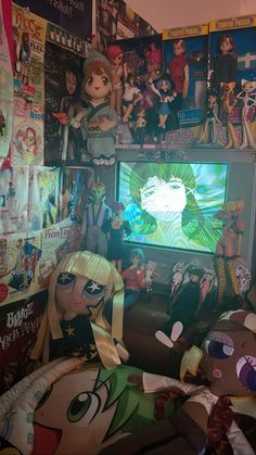 a room filled with lots of anime dolls and posters on the wall above it is a flat screen tv