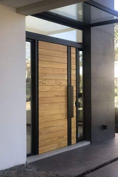 an entrance to a building with wooden doors and glass panels on the front door,