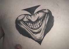 a close up of a person's chest with a tattoo of a joker face