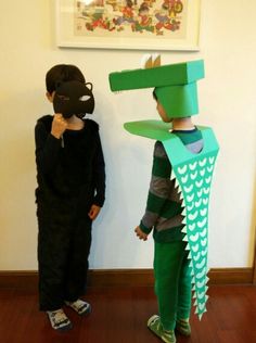 two children in costumes standing next to each other with paper hats on their heads and hands