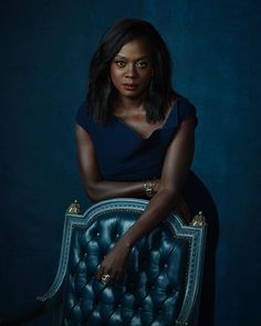 a woman sitting on top of a blue chair with her hand on the back of it