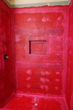 a bathroom with red paint on the walls, and a square hole in the wall